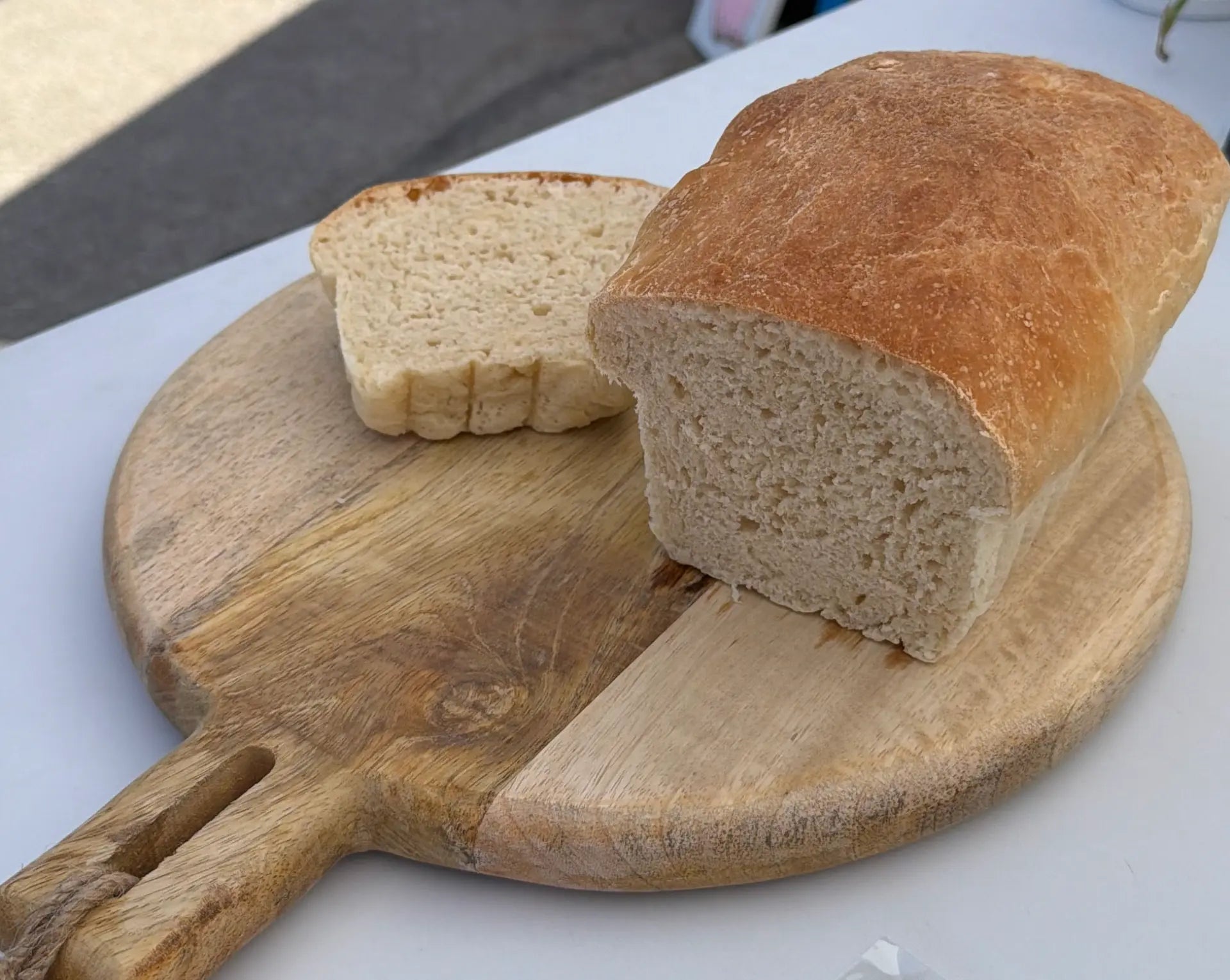 Round artisan sourdough loaf with a scored golden crust on a wooden cutting board
